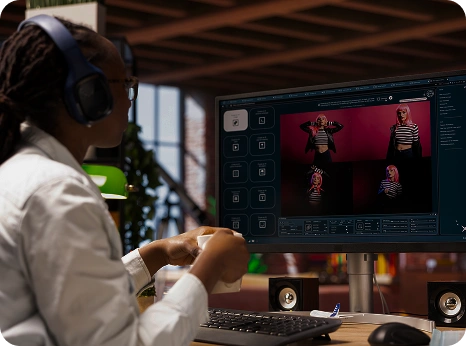 Iemand met een koptelefoon op bewerkt op een computer foto’s van een model in een gestreept shirt. De setting is een modern, open kantoor met een creatieve sfeer
